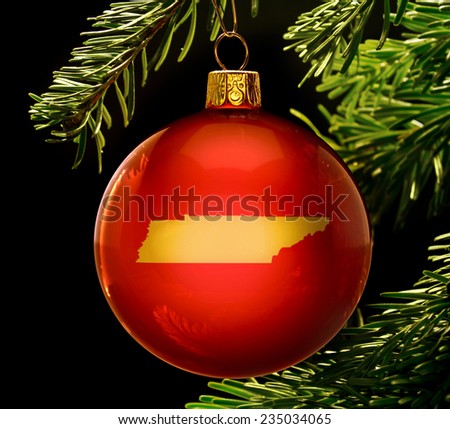 A red bauble with the golden shape of  Tennessee hanging on a christmas tree isolated on black.(series)