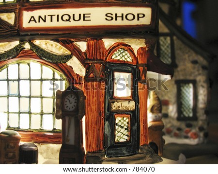 The glow from the front windows of an antique shop in a miniature Christmas village display.