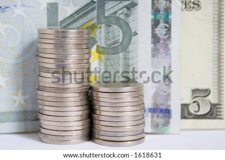 Stack of five cent nickels in front of a five Euro bill and a five dollar American bill, in monochrome with blue toning.