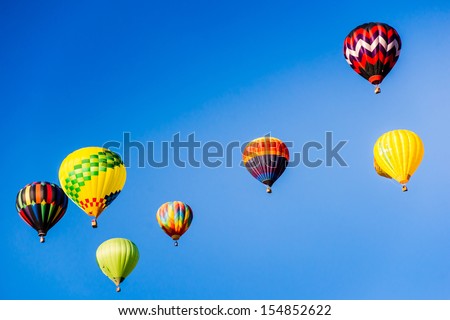 Hot air balloons brighten the blue morning sky in a colorful display of lighter than air flight