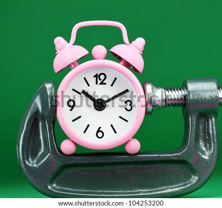 A pink alarm clock placed in a Grey clamp against a green background, asking the question do you manage your time effectively.