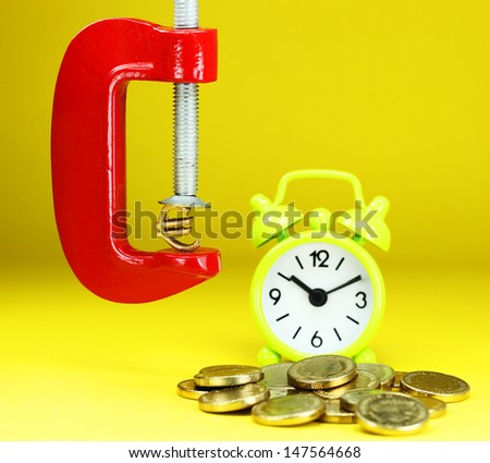 A Gold Euro Symbol in a red vice, with a green clock resting on some gold coins with a pastel yellow background, asking the question how far will the Euro be squeezed.