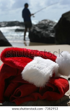 Father Christmas on Boxing Day relaxing fishing after the busiest night of the year, showing his hat and clothes  resting on the beach and the ocean in the background