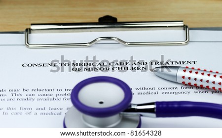 A purple colored stethoscope on a metal  clipboard along with a pen for you to sign a  medical consent form for a minor.