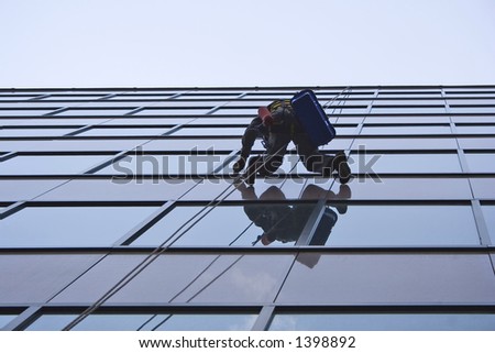 window washer hanging on a rope from a tall business building