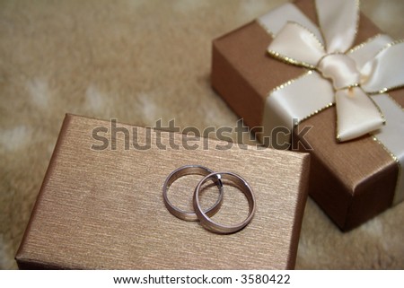 A pair of platinum wedding rings atop an elegant gift box.