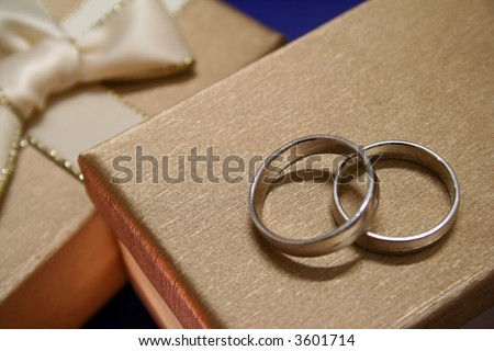 A pair of wedding rings on top of exquisite gift boxes.