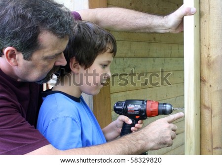 father teaching son to use a drill