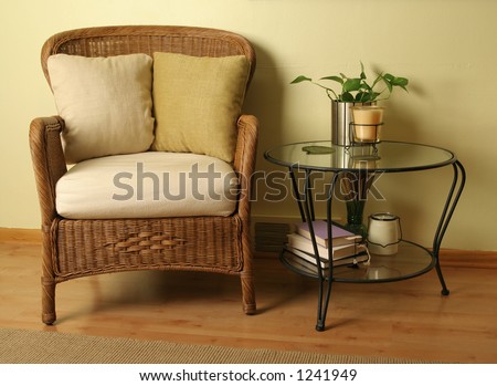 Wicker arm chair and glass table with various items