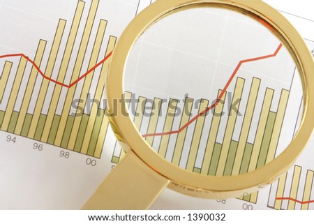 A magnifying glass focusing on a positive earning chart.