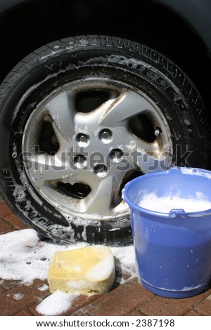Bucket of soapy water by wheel of car
