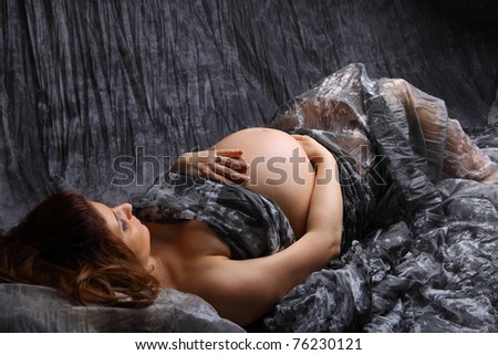 Beautiful Pregnant woman laying on the floor with chiffon on