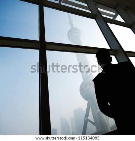 SHANGHAI - NOV. 20:  Unidentified man stands in front of windows  and  Shanghai landmark-Oriental Pearl Tower, on November 20, 2010 in Shanghai, China. One of the Top Ten Shanghai Attractions.