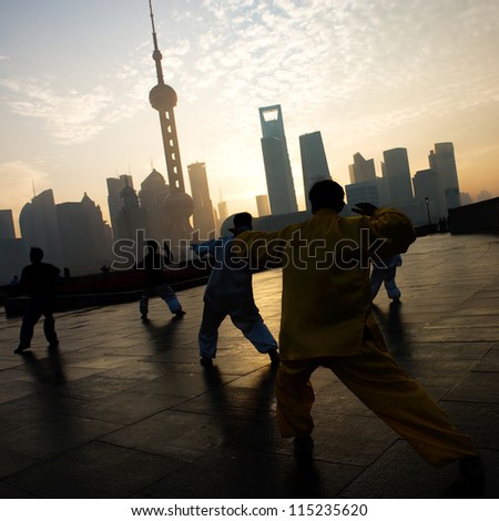 SHANGHAI - NOV. 21:  People practice Taiji on the Bund , Oriental Pearl Tower in the distance, on November 21, 2010 in Shanghai, China.One of the top ten attractions in Shanghai.
