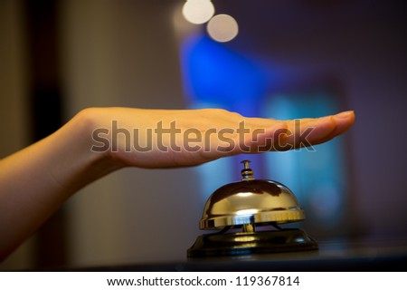 Hand ringing in service bell on wooden table.