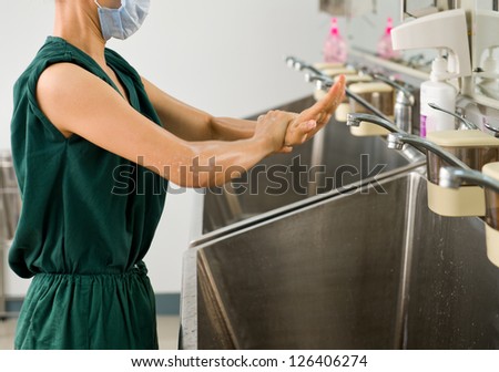 Female doctor washing hands before operation.