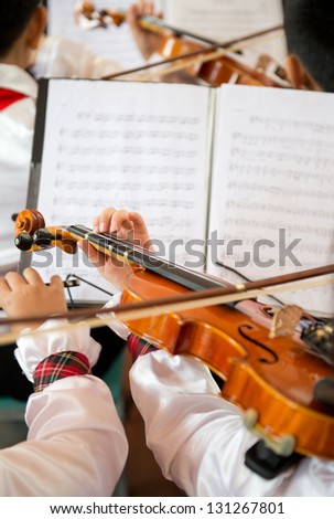 The pupils playing the violin in front of sheet music.