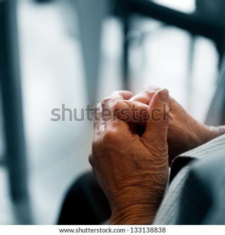 Old woman\'s hands clasped praying.