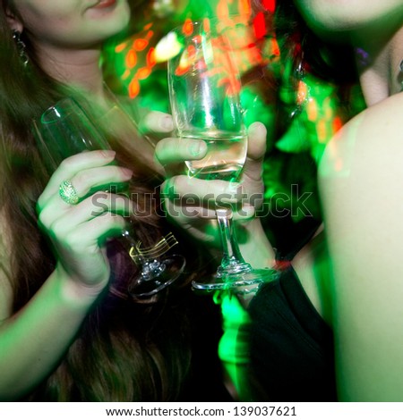 Two young woman in club with glass of wine in hand.