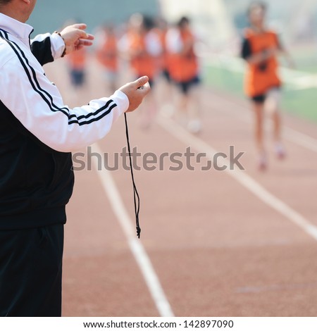 Close-up of a man holding a stopwatch to measure performances of the runners in a stadium