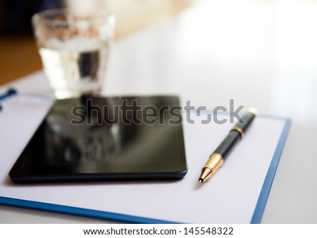 Modern workplace with digital tablet, pen and papers.