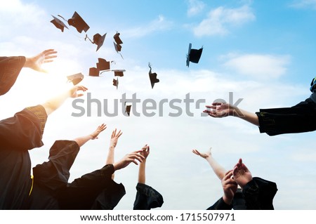 Graduating students hands throwing graduation caps in the air.