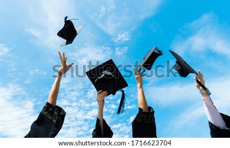 Four graduates throwing graduation hats in the air.