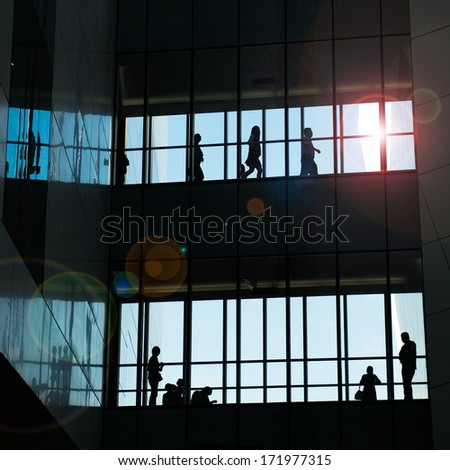 silhouettes of business people rushing at modern office building.