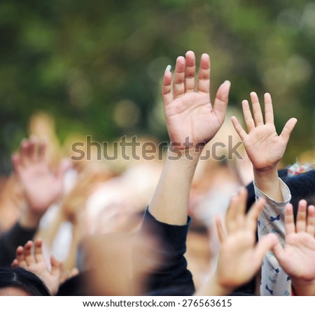 Many hands raised in a crowd of people