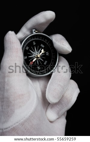 Hand holding the compass isolated on black background.
