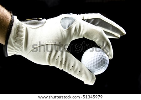 golfer wearing a golf glove holding a ball with his fingers isolated on black