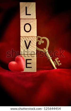Gold key with wooden block letters that spell the word love