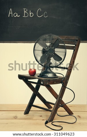 Old fan with apple on chair in school room