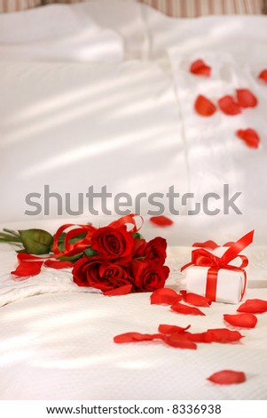 Red roses on a bed with crisp white sheets