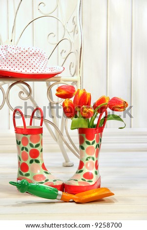 Iron chair with little rain boots and tulips beside