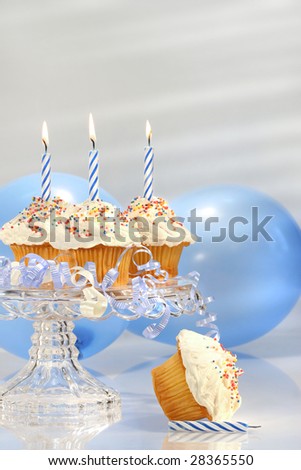 Birthday cupcakes with blue candles and balloons