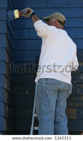 man standing on ladder painting outside of house