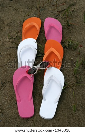 colorful beach shoes and sunglasses on sand