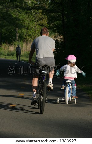 father and daughter riding bikes on path
