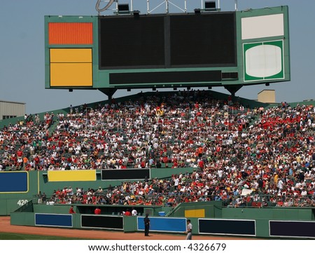 baseball fans sitting in stands under large signs