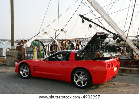 red corvette in front of boat harbor