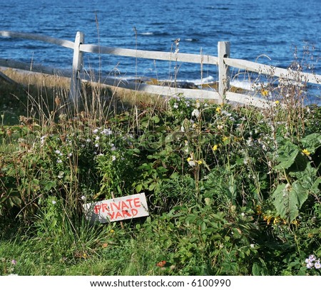 scenic landscape with flowers,fence, and ocean; private yard sign