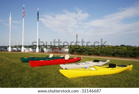 colorful kayaks on grass near boat harbor