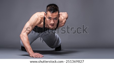 Young asian man workout over grey background - one handed push-up