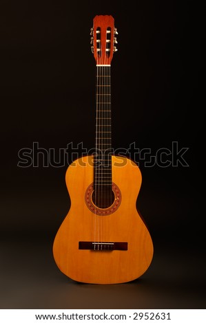 Acoustic guitar over black background standing position