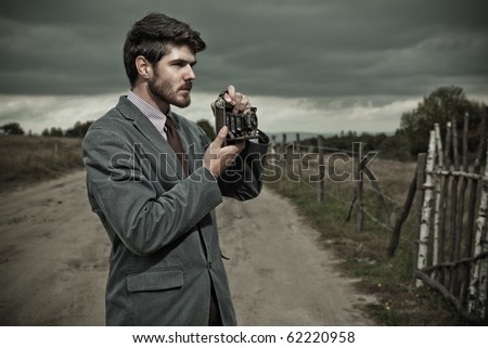 Vintage Photographer holding  a folding camera in his hands