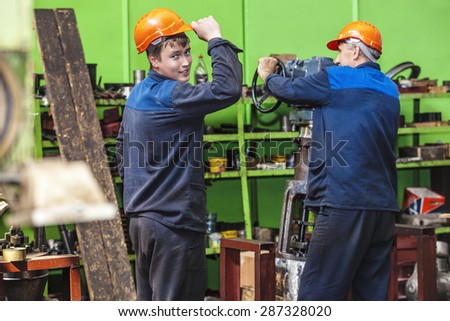 Men work on the old factory for the installation of equipment in protective helmets