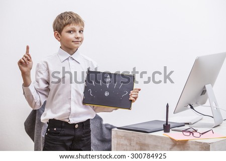 Boy child with a computer, in the office in a white shirt businessman. Studio, technology, monitor, ideas, communication.
