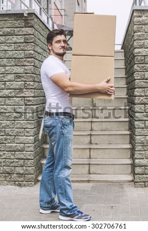 Porter, the man with cardboard boxes in the hands of a strong, delivery to the door. Fast delivery, reliability, deliveryman.