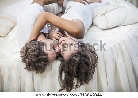 Couple man and woman lay cuddling on the bed at home. Love, family, relationships